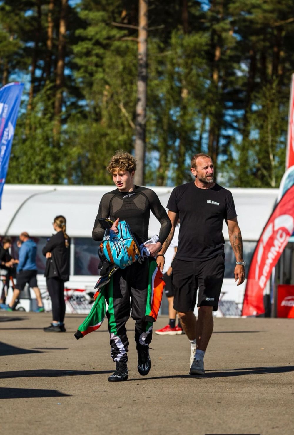 Alexander Dahlström walking through the paddock with his father